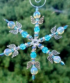 a snowflake made out of glass beads and other items in front of some trees