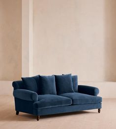 a blue couch sitting on top of a hard wood floor next to a white wall