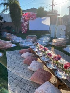 a long table with plates and flowers on it in the middle of a backyard area