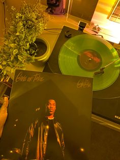 a record player holding up a green vinyl album