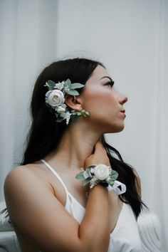 a woman with flowers in her hair is posing for the camera and looking off to the side