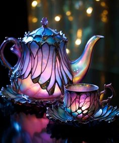 a glass tea pot and saucer sitting on top of a table with lights in the background