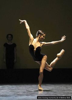 a woman in black leotard doing a dance move on the floor with her legs spread out