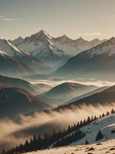 the mountains are covered in fog and low lying clouds as the sun shines on them