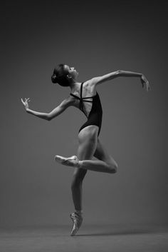 a woman in a leotard and ballet shoes is doing a dance move with her arms outstretched