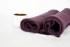 two rolled up purple cloths sitting next to each other on a white tablecloth