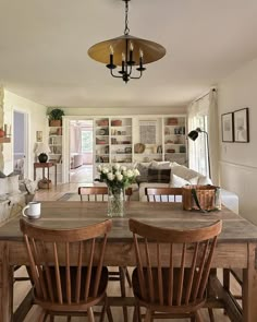 a dining room table with four chairs and a vase on top of it in front of a fireplace