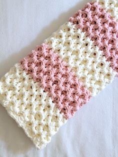 a pink and white crocheted dishcloth laying on top of a white surface