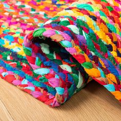 a multicolored rug is laying on top of a wooden floor and it's rolled up