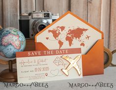 an orange and white save the date card next to a camera, map, and globe