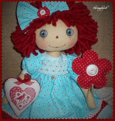 a doll with red hair and blue dress holding a heart shaped object in her hand