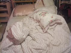 an unmade bed with pink and white sheets