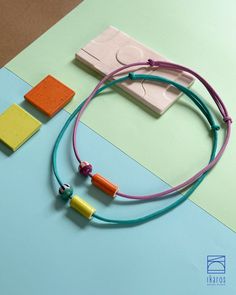 two necklaces on a blue and green table with some colored blocks next to them