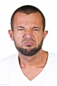 a man with a beard and white shirt is making a face while looking at the camera