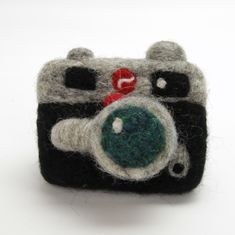 a small camera with a green lens on it's front and black body, sitting on a white surface