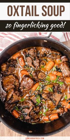 a skillet filled with beef and carrots on top of a wooden table