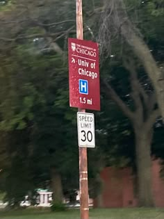 a red street sign sitting on the side of a road next to a lush green park