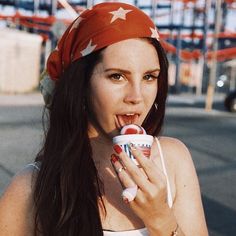 a woman eating an ice cream cone with stars on her head and wearing a bandana