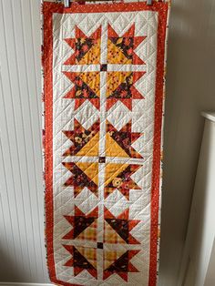 an orange and yellow quilt hanging on the wall