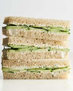 three sandwiches stacked on top of each other with cucumber and cream cheese in between