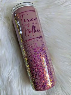 a pink and purple glitter tumbler sitting on top of a white fur covered floor