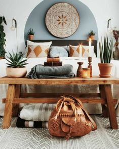 a bed with a wooden bench in front of it and potted plants on the side