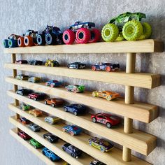 a wooden shelf with many toy cars on it and two shelves holding them up against the wall