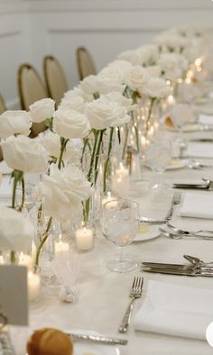 a long table is set with white flowers and candles for an elegant dinner or reception