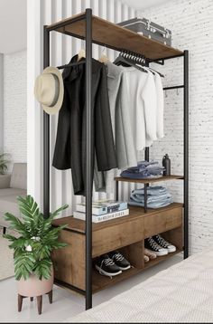 an open closet with clothes and shoes on shelves next to a potted plant in front of a white brick wall