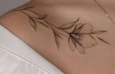 the back of a woman's shoulder with a tattoo on her left arm and flowers