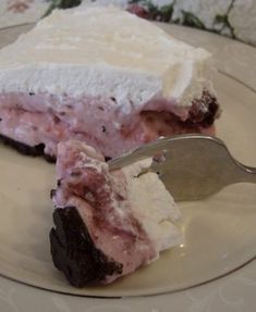 a piece of ice cream cake on a plate with a fork and spoon next to it