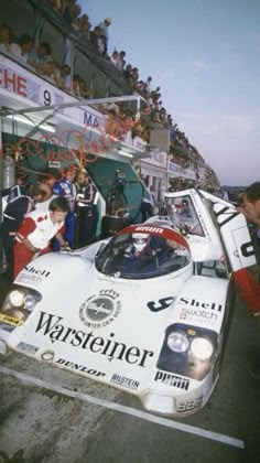 an old photo of a race car with people around it