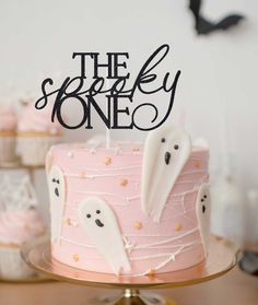 a pink cake with white frosting and spooky ghost decorations is on a table