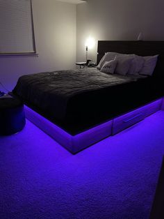 a large bed with purple lights on it in a room that has carpeted flooring