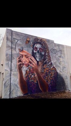 a large painting on the side of a building with a woman holding a cell phone to her ear