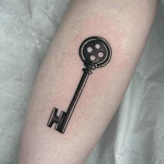 a black and white photo of a key tattoo on the left arm, with dots in it