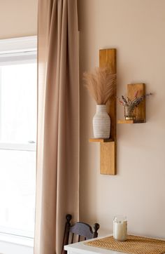 a room with a table, chair and vase on the wall next to a window