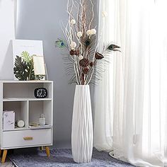 a white vase filled with flowers on top of a blue rug next to a window