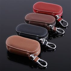 four leather key cases are lined up on a black surface and one is red, the other is brown