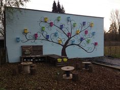 a tree with colorful cups on it is painted on the side of a building,