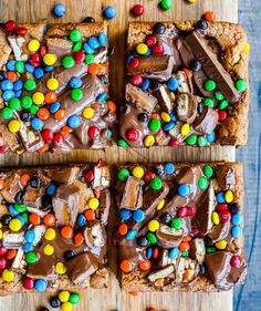 three pieces of chocolate m & m bars on a cutting board with candy and candies