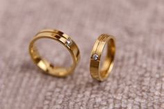 two gold wedding rings sitting on top of each other