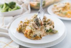 broccoli and chicken casserole on a white plate with a fork in it