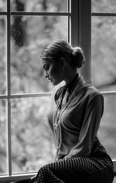 a woman sitting on a window sill looking out the window