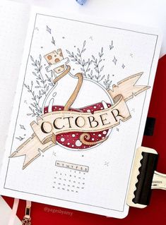 an open notebook with the word october on it next to a pen, scissors and other items