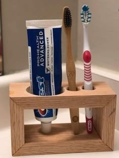 two toothbrushes and one tube of toothpaste are in a wooden holder