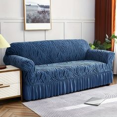 a blue couch sitting on top of a hard wood floor next to a table and lamp