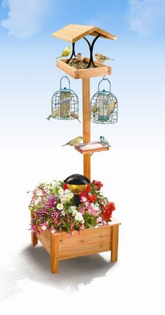 a wooden bird feeder with two birds on it and flowers in the planter below