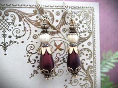 This listing is for my Vintage Victorian Style Large Czech Glass and Glass Pearl Teardrop Dangle Earrings in Ivory and Burgundy Wine. These stunning earrings are a classic vintage-inspired design with a classic romantic appeal. Elegant matte glass pearl teardrop beads in deep burgundy red are accented with highly-detailed bead caps and glittering rhinestones. Finished with beautiful Czech glass ivory beads with brass flecks. The closures are lever back style.  *Earrings measure approx. 2" long. Ivory Earrings, Teardrop Dangle Earrings, Deep Burgundy, Teardrop Beads, Burgundy Wine, Vintage Victorian, Vintage Inspired Design, Stunning Earrings, Style Earrings