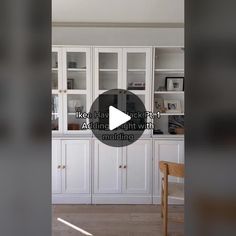 a white kitchen with lots of cabinets and cupboards on the wall, along with a wooden dining table